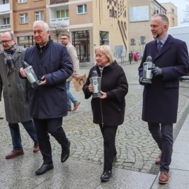 powiększ zdjęcie: Znicze i kwiaty przed tablicą upamiętniającą Jerzego Szmajdzińskiego
