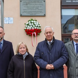 powiększ zdjęcie: Znicze i kwiaty przed tablicą upamiętniającą Jerzego Szmajdzińskiego