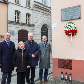 powiększ zdjęcie: Znicze i kwiaty przed tablicą upamiętniającą Jerzego Szmajdzińskiego